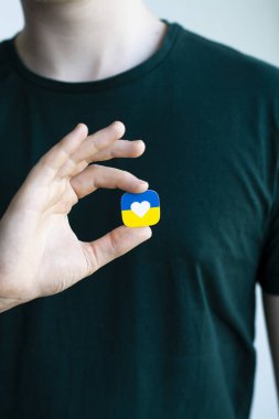 Rusya ile savaşta Ukrayna 'ya destek. Genç bir adam Ukrayna 'nın stilize edilmiş bayrağını kalbinin yanında tutuyor. Kavramsal fotoğraf.