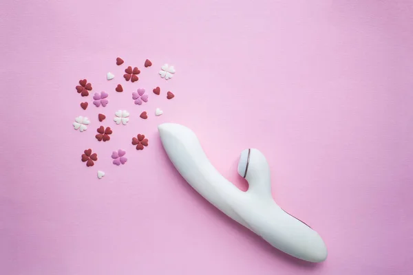 大人のための白いバイブレーターのおもちゃはピンクの背景にあり 装飾的な心の隣にオーガズムを模倣しています 概念写真 — ストック写真