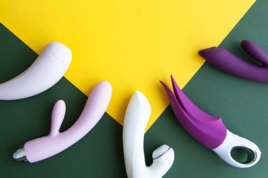 Yeşil ve sarı arka planda farklı seks oyuncakları koleksiyonu. Yetişkinler için seks oyuncakları, vibratörler, klitoral uyarıcılar.
