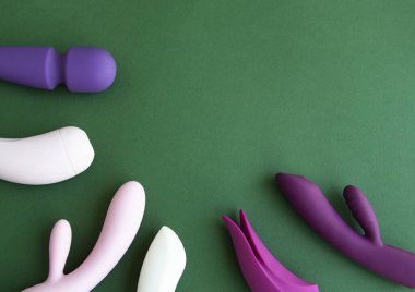 Yeşil arka planda farklı seks oyuncakları koleksiyonu. Yetişkinler için seks oyuncakları, vibratörler, klitoral uyarıcılar.