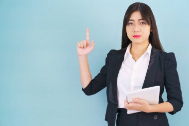 Takım elbiseli genç kadınlar dijital tablet bilgisayarlarını mavi arka planda tutuyorlar.