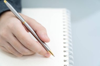 Ofisteki not defterine yazı yazan bir iş kadını elinde kalemle masa başına not defteri yazan bir kadın.