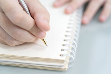 Ofisteki not defterine yazı yazan bir iş kadını elinde kalemle masa başına not defteri yazan bir kadın.