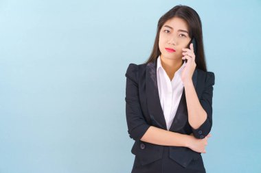 Takım elbiseli genç kadınlar telefonlarını mavi arka planda tutuyorlar.