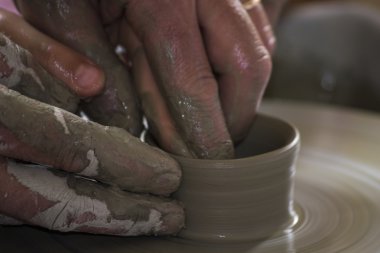 Potter çömlek çarkında seramik tabağı şekillendiriyor.