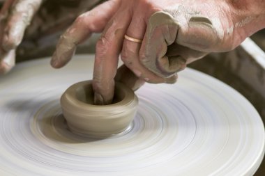 Potter çömlek çarkında seramik tabağı şekillendiriyor.