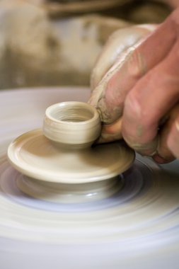 Potter çömlek çarkında seramik tabağı şekillendiriyor.
