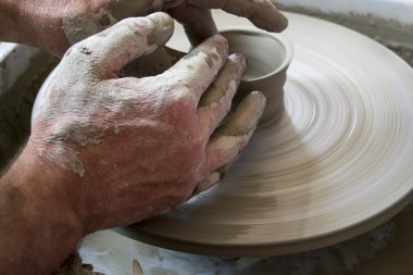 Potter çömlek çarkında seramik tabağı şekillendiriyor.