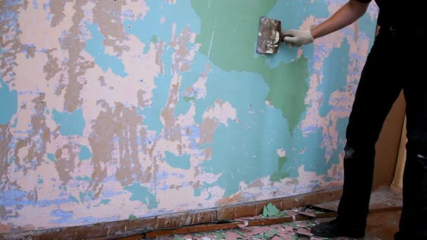 Працівник очищає стіну шпателем від старої фарби — стокове відео