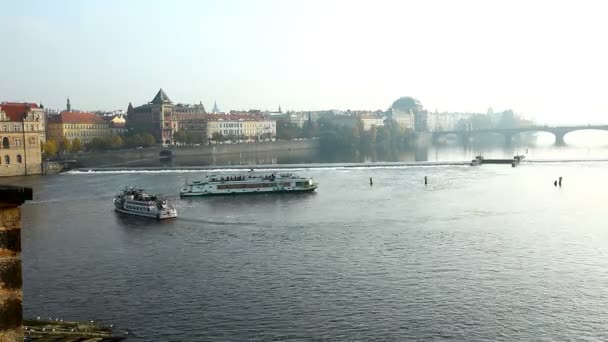 Туристы путешествуют по осенней реке с Пражского моста — стоковое видео