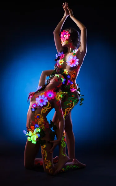 Nude women with glow uv body art and flowers — Stock Photo, Image