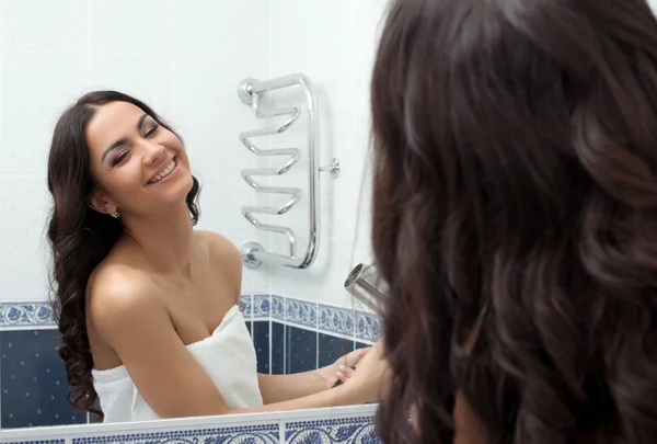 Όμορφη γυναίκα με στεγνωτήρα μαλλιών στο μπάνιο — Φωτογραφία Αρχείου
