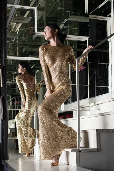 Young woman in gold dress on stairs — Stock Photo, Image