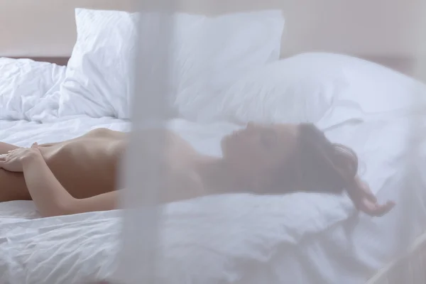 Nahá žena leží na posteli — Stock fotografie