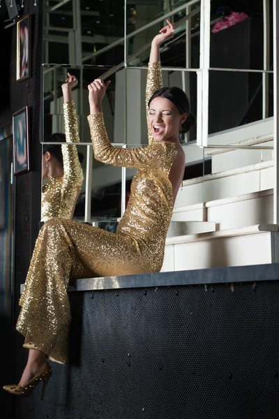 Junge Frau im goldenen Kleid hat Spaß am Stehtisch — Stockfoto