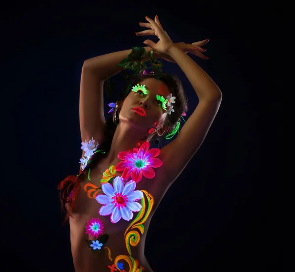 Amazing woman in glowing flowers under uv light — Stock Photo, Image