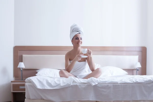 Genç esmer kadın yatakta kahve ile rahatlayın — Stok fotoğraf