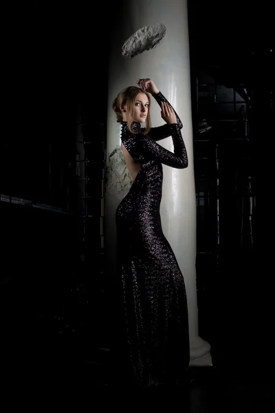 Pretty young woman in black dress near column — Stock Photo, Image