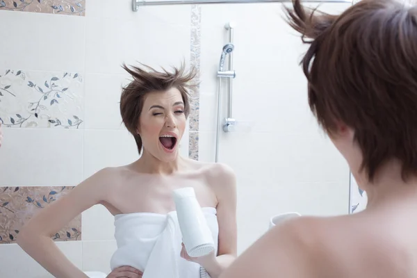 Chica alegre posando con secador de pelo cerca del espejo —  Fotos de Stock