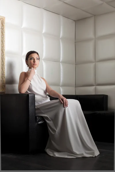 Beautiful young woman on huge white sofa — Stock Photo, Image