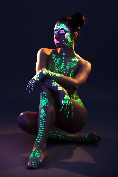 Slim flicka med UV-glödande makeup poserar i mörkret — Stockfoto