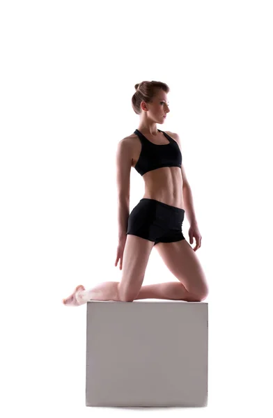 Young athletic brunette posing on cube — Stock Photo, Image