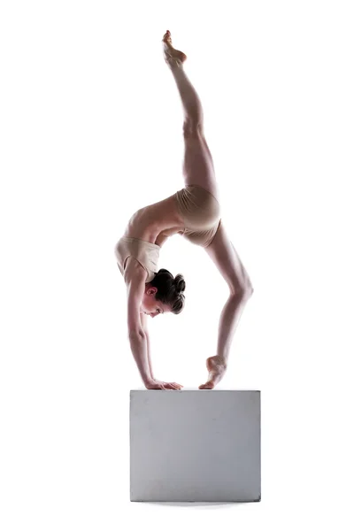 Slim woman balancing on cube in studio — Stock Photo, Image