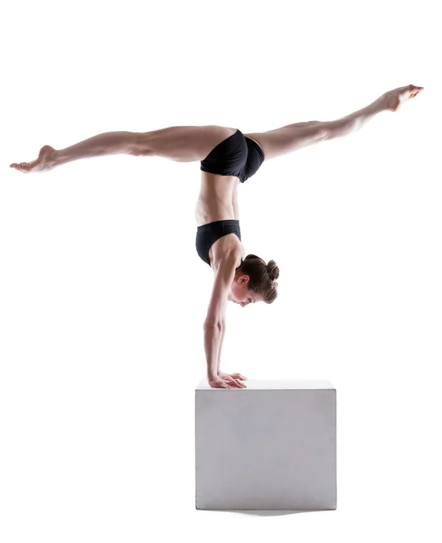 Flexibele gymnast balanceren op kubus in studio — Stockfoto