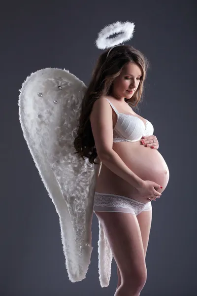 Hübsche schwangere Frau posiert im Engelskostüm — Stockfoto