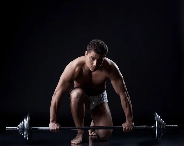 Sexual muscular chico posando con barbell en estudio — Foto de Stock