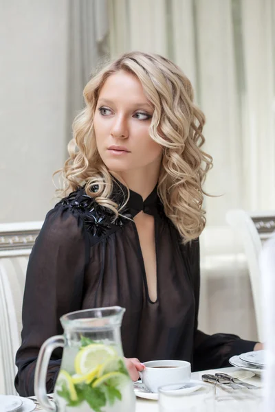 Vackra unga modell poserar sittande vid bord — Stockfoto