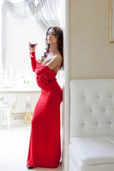 Morena sedutora posando em vestido vermelho longo — Fotografia de Stock