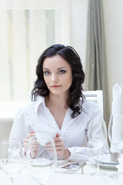 Portrét atraktivní bruneta sedí u stolu — Stock fotografie