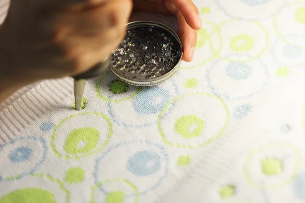 Woman glueing sequins to colorful fabrics — Stock Photo, Image