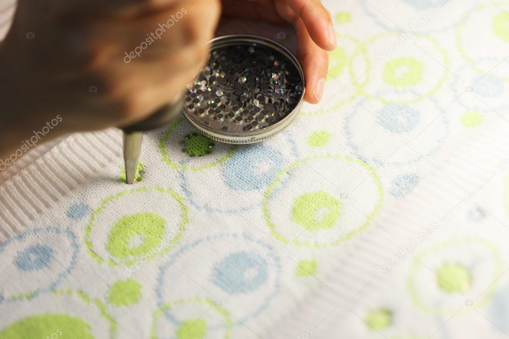Woman glueing sequins to colorful fabrics