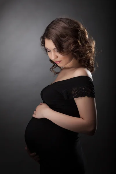 Schöne schwangere Frau im schwarzen Kleid — Stockfoto