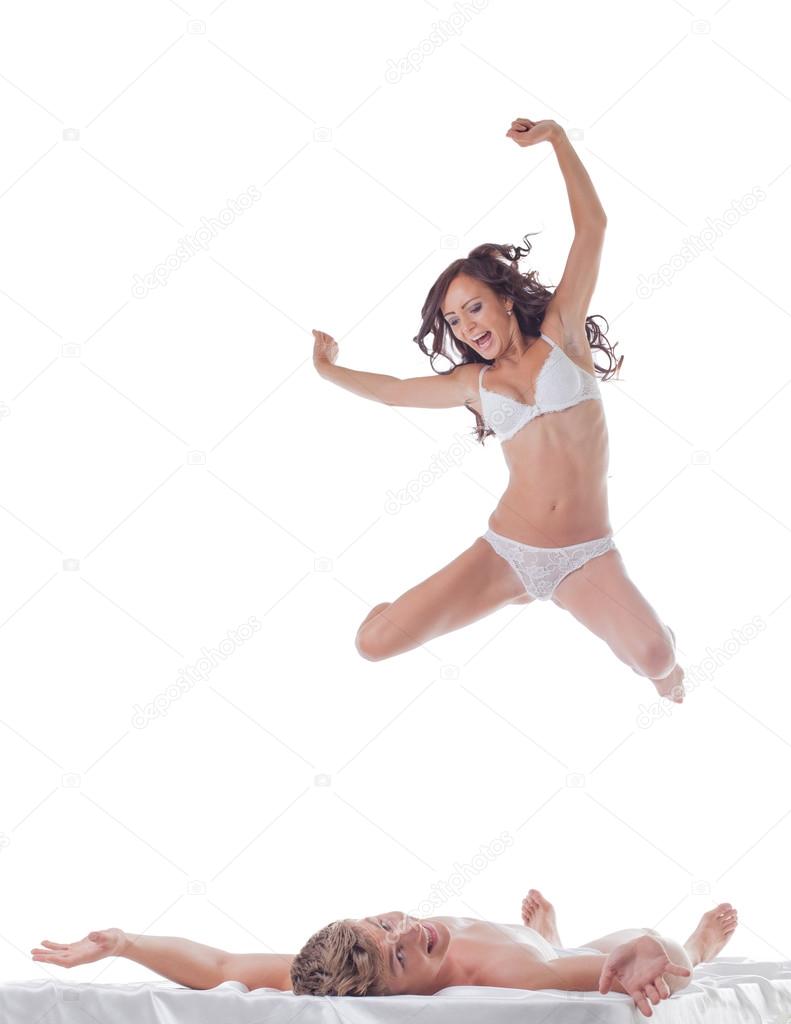 Cheerful slim woman jumping into bed with sexy guy