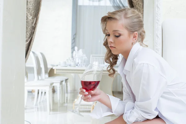 Mooi meisje kijkt zorgvuldig naar glas wijn — Stockfoto