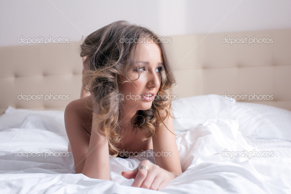 Portrait of sexy curly model posing in bedroom