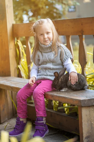 Pretty little girl sitting in gazebo with rabbit — Stock Photo, Image