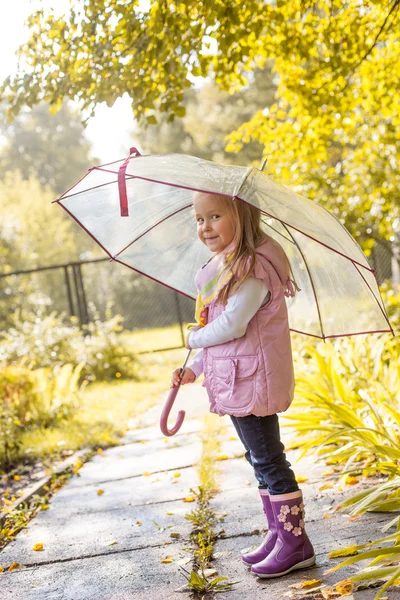 Slyly smiling girl posing under umbrella in park — Stock Photo, Image
