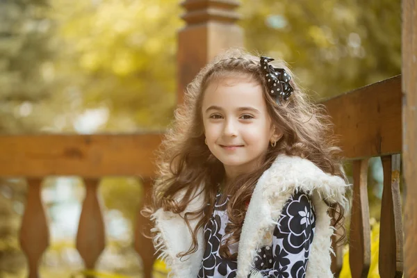 Módní kudrnaté malá brunetka se usmívá na kameru — Stock fotografie