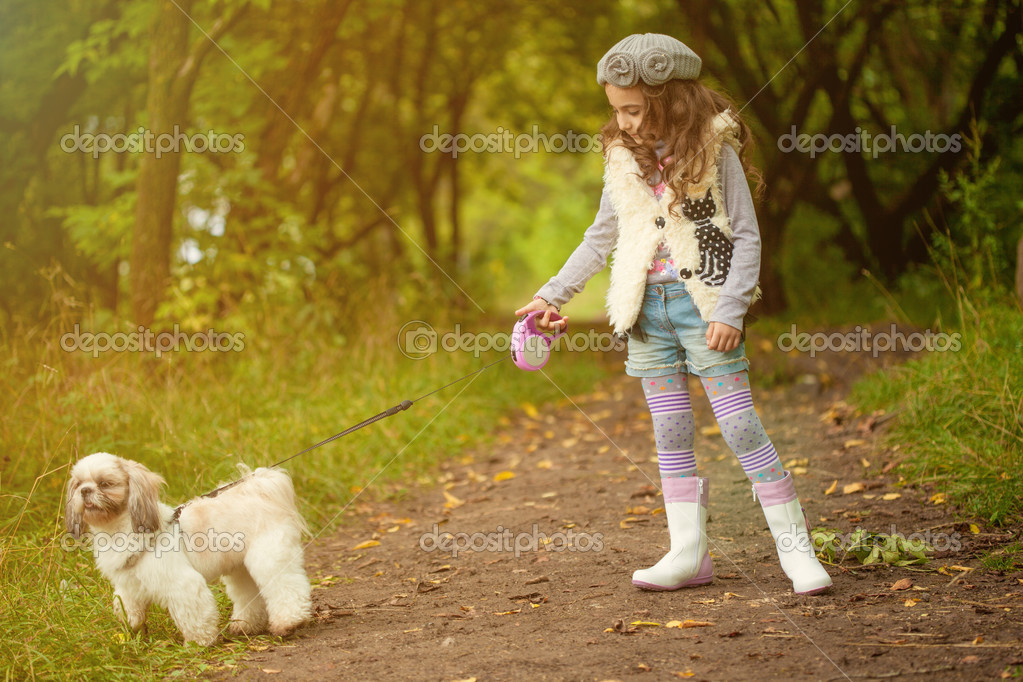 Niedliche lockige Mädchen, die mit Hund im Park spazieren gehen