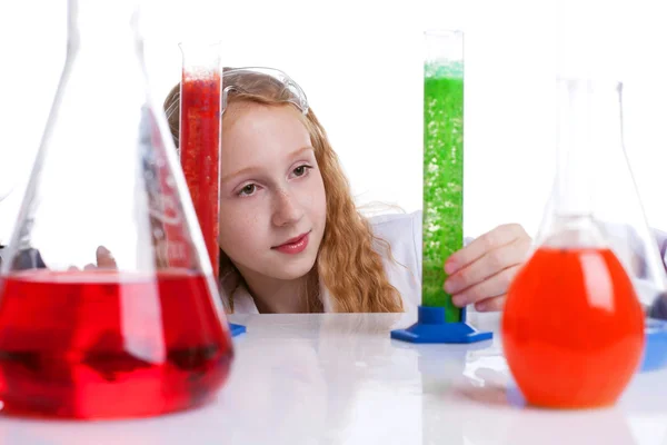 Linda estudante olhando para frascos com produtos químicos — Fotografia de Stock