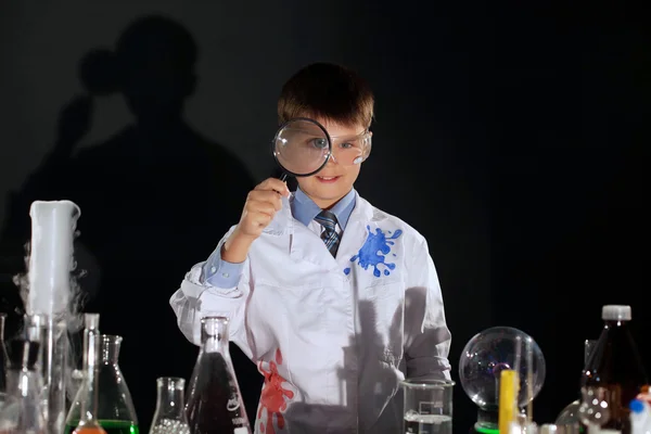 Smiling schoolboy looking through magnifying glass — Stock Photo, Image