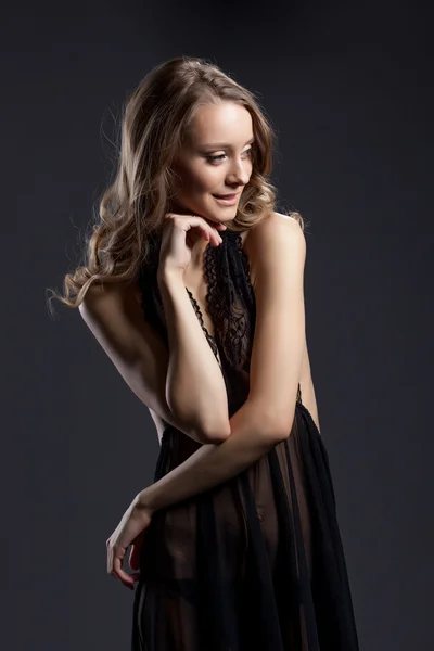 Smiling shy woman posing in black erotic negligee — Stock Photo, Image