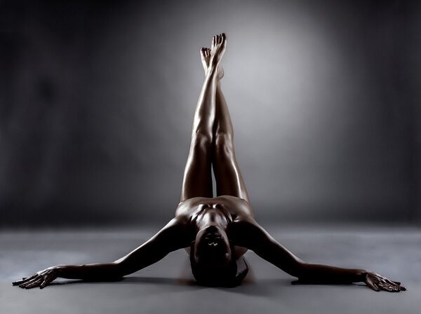 Silhouette of excited naked woman with slim legs posing in studio