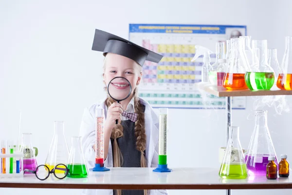 Funny little girl posing with magnifier in lab — Stock Photo, Image