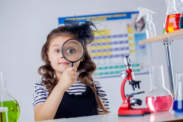 Cute dark-haired girl looking through magnifier — Stock Photo, Image
