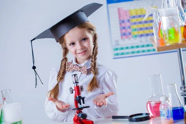 Usmívající se malý chemik pózuje s mikroskopem — Stock fotografie